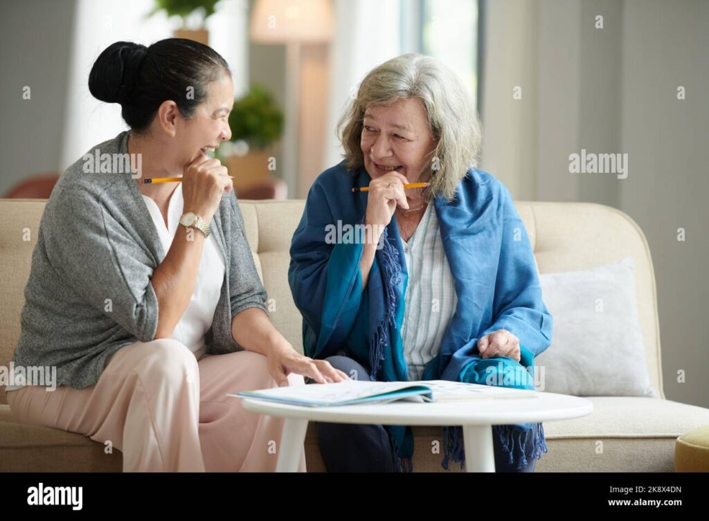 Joyful Aged Female Friends Thinking On Answer For Crossword Puzzle 